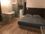 Két személyre asztal, székek, ágy. Háttérben jól felszerelt konyha: hűtő, tűzhely, konyhaszekrény. Budapest VIII. kerületében található a szoba.